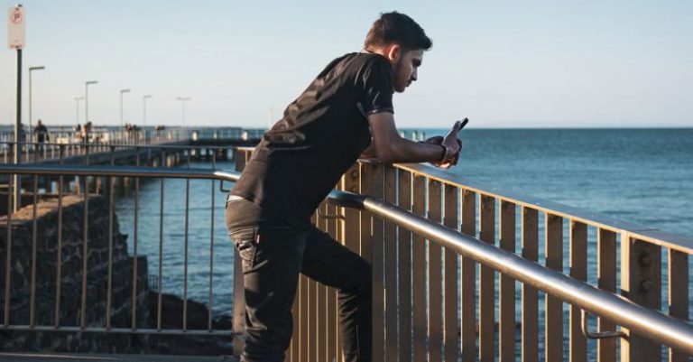 Lean Thinking - A man standing on a railing looking at the ocean