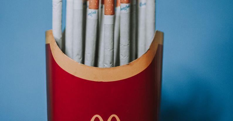 Habit Stacking - Red and yellow paper packet from french fries filled with cigarettes on blue background