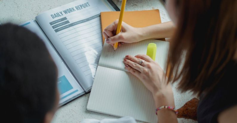 Daily Planning - From above of crop faceless female students taking notes while working on daily work report together