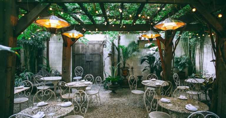 Setting Priorities - Cafe with setting on ornamental tables near chairs under decorative lamps in backyard on summer day